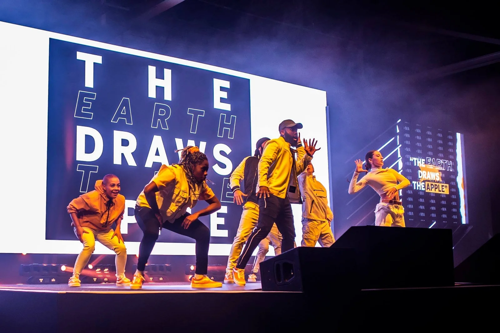 Dancers in yellow performing together on stage